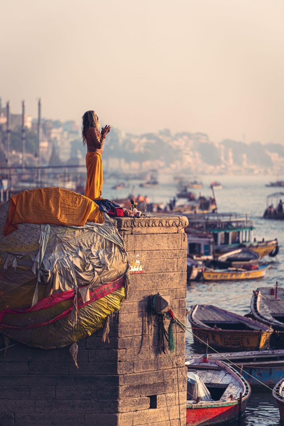 Morning prayers on a ghat in Varanasi, boats on the river behind